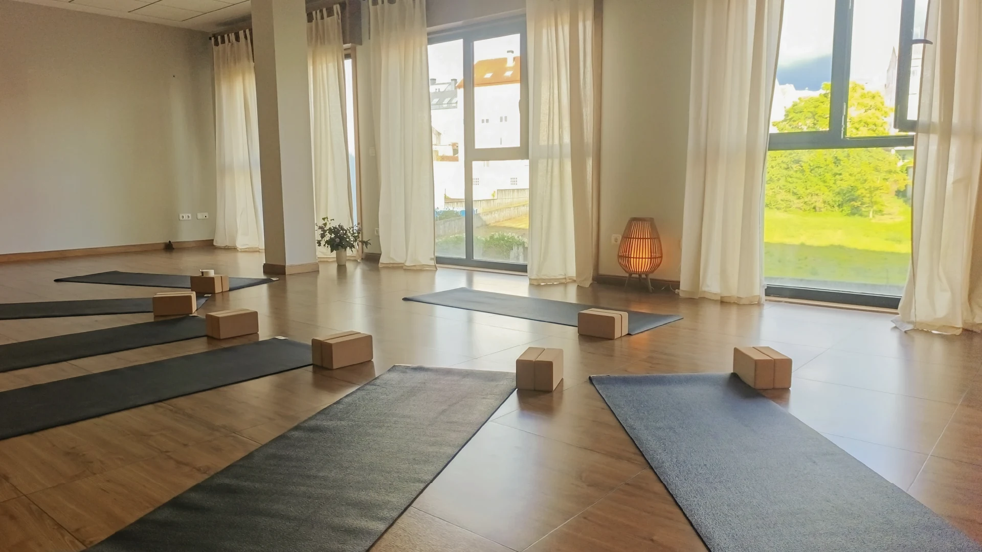 Espacio de clases de yoga en Carballo con luz natural, esterillas y lámpara cálida