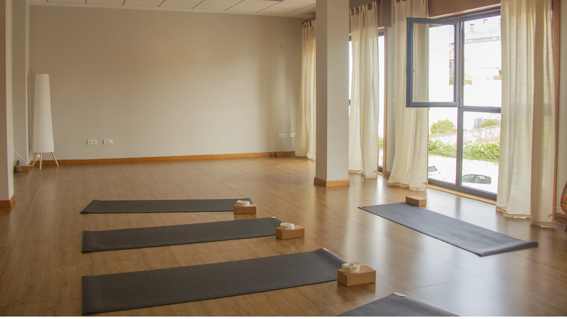 Sala de yoga luminosa de Emana Yoga Studio en Carballo con esterillas, bloques y grandes ventanales