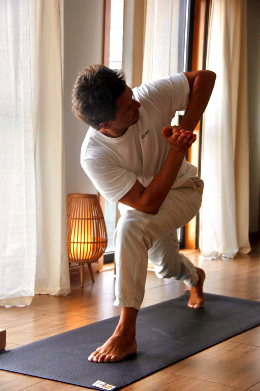 Profesor de yoga practicando junto a la ventana en Emana Yoga Carballo